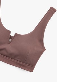 Ruskea pehmeä kangasliivi, jossa on syvä V-kaula-aukkosuunnittelu, leveät hihnat ja sileät ompeleet. Ilman joustavaa rautaa, saumaton rakenne.