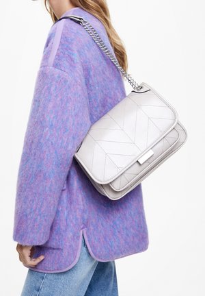 Quilted white leather handbag with a silver chain strap, paired with a purple textured sweater featuring a rounded hem and contrasting trim.