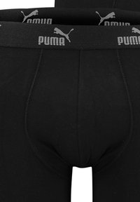 Schwarze Boxer-Briefs aus dehnbarem Material mit enger Passform. Mit einem grauen elastischen Bund mit dem Puma-Logo und einem Vorderpouch-Design.