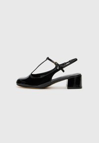 Black patent leather slingback shoe with a T-strap design, rounded toe, and a low block heel. Features a flexible ankle strap.