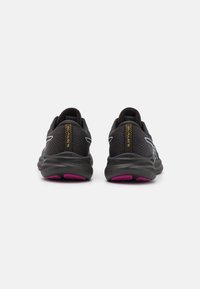 Baskets de sport noires avec une tige en mesh respirant, accents roses sur la semelle et détails réfléchissants sur les côtés, conçues pour le confort et le soutien.