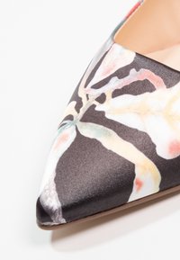 Scarpa a punta realizzata in satin nero con un motivo floreale dai colori tenui. La suola è marrone, evidenziando una superficie liscia.