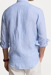 Světle modrá a bílá pruhovaná košile s dlouhým rukávem vyrobená z tkané látky, s klasickým límečkem a ohrnutými manžetami. Zadní pohled ukazuje klasický střih.