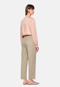 Light pink satin blouse with long sleeves, paired with beige high-waisted trousers and blush flats, features a relaxed fit and button accents.