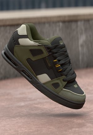 Green and gray sneaker with leather and textile upper, textured accents, padded collar, and black rubber sole. Features yellow eyelets and logo.