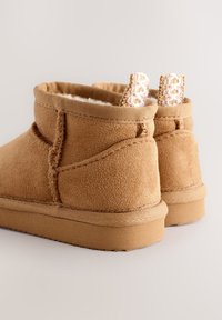 Bottines en daim marron avec une doublure intérieure douce, dotées de languettes en crochet texturé et d'une semelle en caoutchouc robuste.