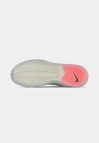 Nikeova potplata s valovitom površinom, prozirna svijetlosiva guma s ružičastim detaljem na peti i crnim logoom.