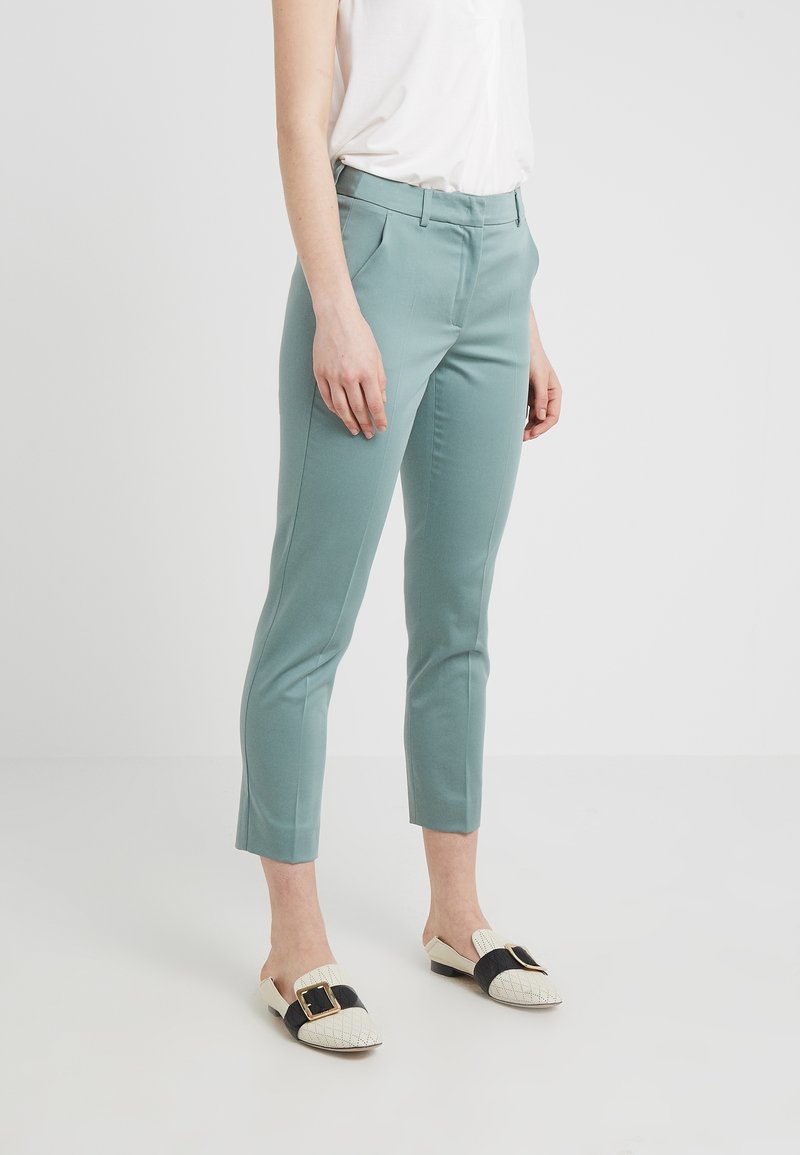 Pantalones cortos de color verde menta con un ajuste entallado, que cuentan con bolsillos laterales y una textura suave, combinados con zapatos de slip-on en blanco y negro.