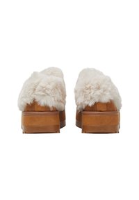 Ein Paar braune Plattform-Slipper mit dicker, weißer, flauschiger Fellbedeckung oben, von hinten vor einem weißen Hintergrund betrachtet.