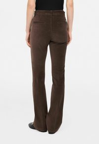 Pantaloni marroni svasati con una texture liscia, dotati di due tasche posteriori e dettagli di cucitura sottili. Ideali per un abbigliamento casual o semi-formale.