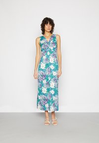 Vestido maxi floral em teal com flores brancas e roxas. Apresenta decote em V, corpete justo e uma saia fluida. Alças finas e comprimento até o tornozelo.