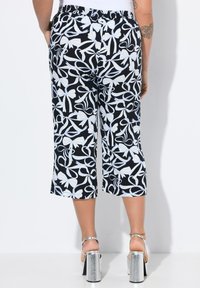 Černobílé květinové vzorované zkrácené kalhoty s elastickým pasem, uvolněný střih a boční kapsy. Stříbrné vysoké sandály.