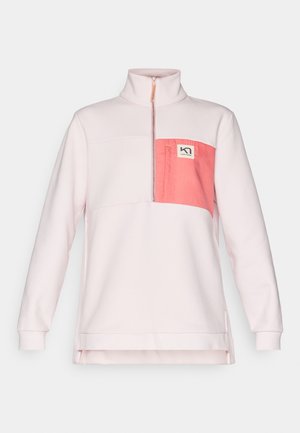 Pull léger rose avec un col haut, doté d'une poche rectangulaire en rose plus foncé et d'un patch logo. Texture douce et coupe décontractée.