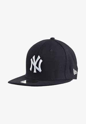 Gorra de béisbol negra de los New York Yankees con logotipo bordado en blanco y visera plana, mostrada en un ángulo ligeramente inclinado sobre un fondo blanco.