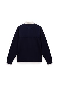 Camisa polo de manga larga en azul marino con un cuello blanco contrastante, textura suave y detalle de costura en el yugo trasero.