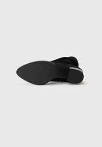 Bottines noires avec une tige lisse, un bout rond, un petit talon et une semelle en caoutchouc texturée pour une meilleure adhérence. Design simple sans embellissements.