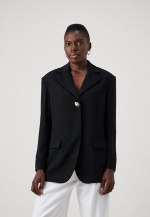 Sort blazer med en enkelt blomstermønstret knap, notch-slids, og to forlommer; glat tekstur og skræddersyet pasform.