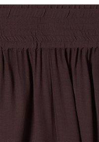 Tissu brun foncé avec texture froncée et ceinture élastique horizontale cousue créant un effet froncé.