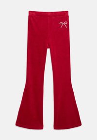 Rode flared broek van fluweel met een kleine strass strikdetail op de linkerbovenheup, weergegeven op een witte achtergrond.