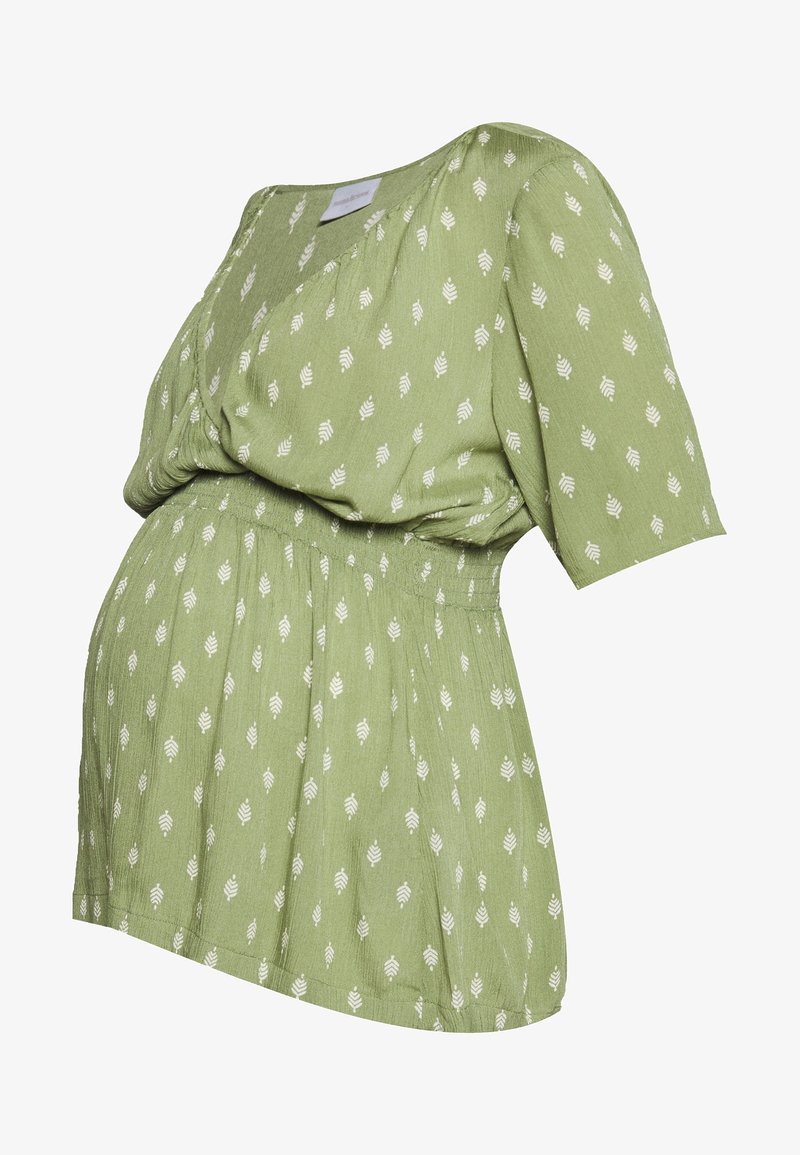 Blusa maternità verde con motivo a foglie bianche, maniche corte, scollo a V e vita elastica arricciata.