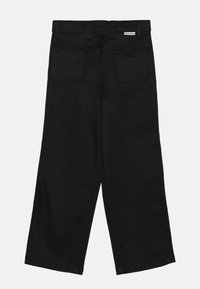 Sorte vide benbukser laget av denim, med to baklommer, glidelås og et merke på midjen. Glatt tekstur.