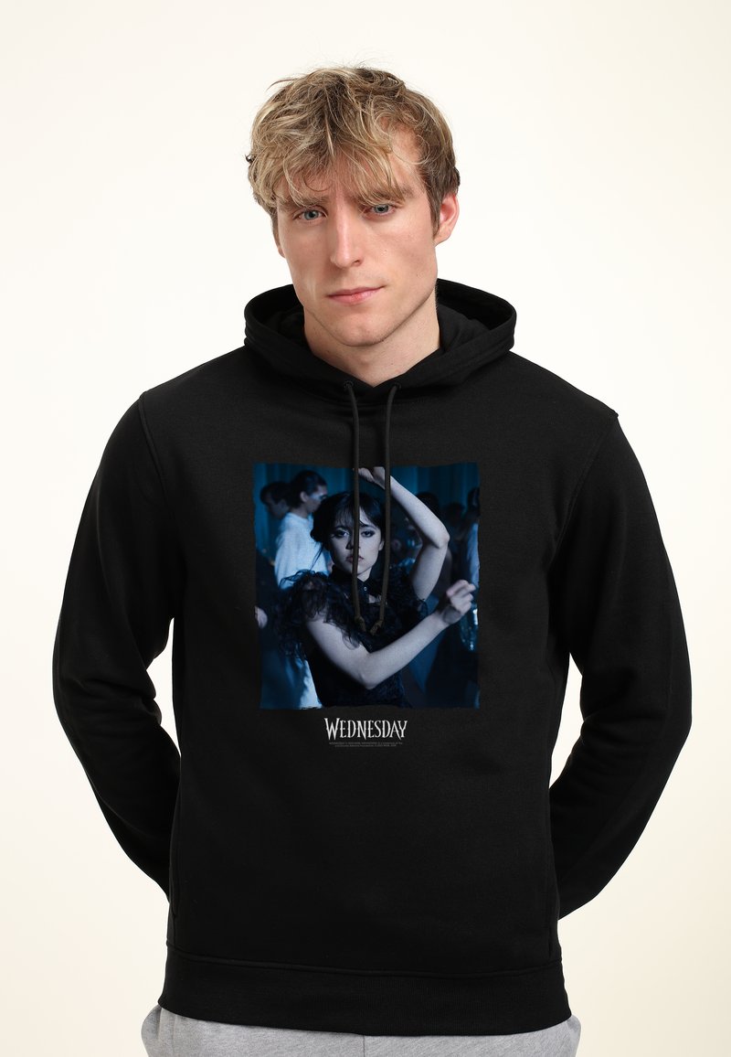 Felpa con cappuccio nera che presenta una stampa grafica di un personaggio con abbigliamento scuro e maniche sovrapposte. Il testo "MERCOLEDÌ" si trova in fondo.