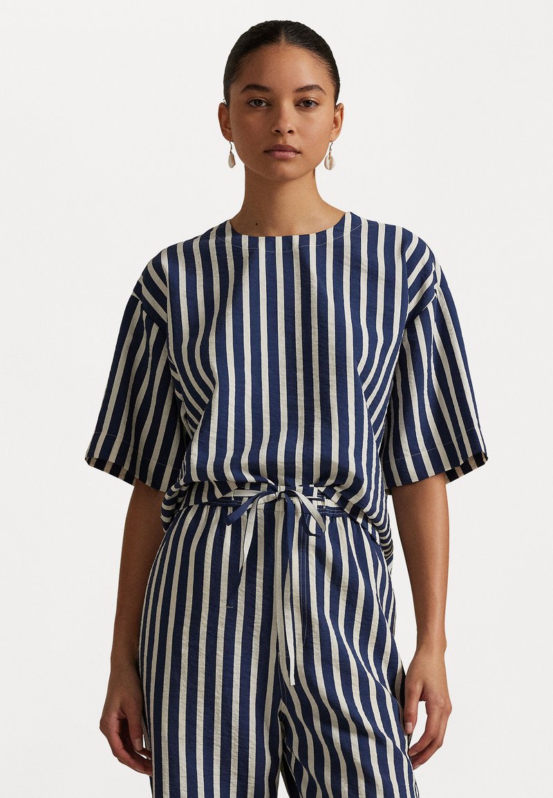 Striped shirt and pants set in navy blue and cream. Features short sleeves, a round neckline, and a tied waistband, made from textured fabric.