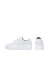 Weiße Ledersneaker mit dicker, geriffelter weißer Sohle, runder Spitze und traditionellem Schnürdesign. Glatte Textur, minimalistischer Stil.