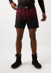 Ανδρικά αθλητικά σορτς σε διαβαθμισμένο χρώμα από μπορντώ σε μαύρο, με μαλακό και ελαφρύ υλικό, και ζώνη με λογότυπο κίτρινης κόμπρας.