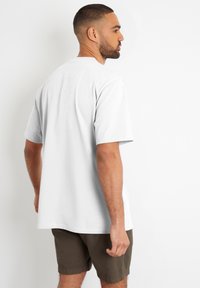 Hvid bomulds t-shirt med korte ærmer, med en afslappet pasform. Sammen med olivengrønne shorts, der viser en afslappet stil.