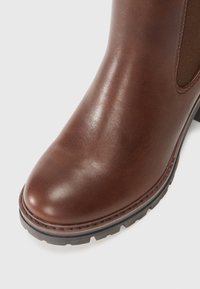 Brune lær ankle boot med en glat finish, elastisk sidepanel og tekstureret gummisål, med en rund tå og syninger.