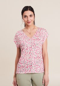 V-Ausschnitt T-Shirt aus leichtem Stoff, mit einem pinken Blattmuster auf hellem Hintergrund, kurzen Ärmeln und lockerer Passform.