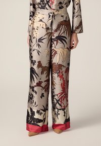 Blumenmusterweite Hosen aus strukturiertem Stoff, in den Farben Gold, Schwarz und Rot mit einem kontrastierenden roten Satinsaum.