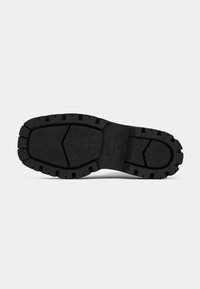 Black rubber shoe sole with a textured surface. Features deep treads and a contoured shape for traction and stability.