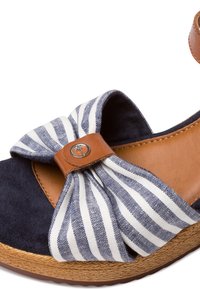 Sandale compensée bleu marine avec nœud en tissu rayé et sangle en cuir tan avec détail bouton rond en métal.