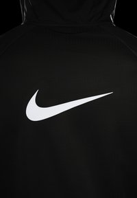 Sudadera deportiva negra con un gran logo de Nike en blanco en la parte posterior. El material tiene un acabado texturizado con una apariencia suave.