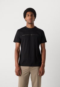 Tricou negru cu mânecă scurtă, fabricat din bumbac, cu guler rotund. Prezentă un logo texturat "ANTONY MORATO" pe piept.