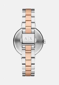 Hõbedane ja roosakuldne roostevabast terasest kell ümmarguse korpuse ja vahelduvate metalllingidega rihmaga. A|X logo pandlale.