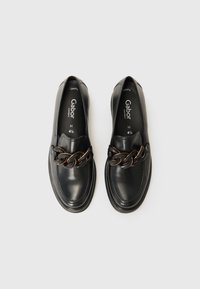Mocassins en cuir noir avec une chaîne décorative sur le devant, un bout arrondi et des coutures texturées. Marque visible sur la semelle intérieure.