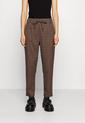Bruine geruite broek met een relaxed fit, elastische tailleband en koord. Gecombineerd met zwarte chunky schoenen en een aansluitend zwart topje.