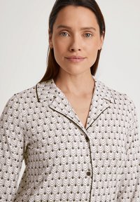 Maglia da pigiama bianca con un motivo a scallop in marrone scuro, caratterizzata da un design con colletto e piping scuro lungo i bordi. Bottoni sul fronte.