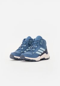 Le scarpe da trekking blu presentano una tomaia testurizzata, tre strisce azzurre, un tallone rinforzato e una suola robusta per la trazione.