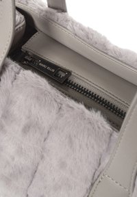 Sac à main gris avec intérieur en peluche, doté d'une fermeture éclair et d'une étiquette de marque métallique. Texture extérieure lisse et doublure douce et duveteuse.