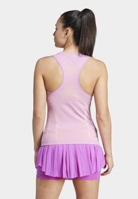 Mouwloos shirt in lichtroze met een textuurdesign, gecombineerd met een geplooide rok in een donkerdere tint roze, met een aansluitende pasvorm en sportieve silhouet.