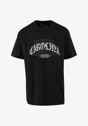 Must näitab musta puuvillast T-särki, millel on julge valge tekst "NORTH CAROLINA" ja väiksem tekst allpool, loodud ülikooli brändimiseks.