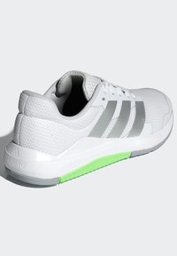 White athletic shoe with mesh upper, gray accents, and a green rubber outsole. Features three gray stripes and textured surface.