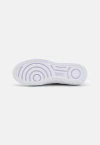 White rubber sneaker sole with a circular pattern and textured edges. Smooth surface with grooves for traction.