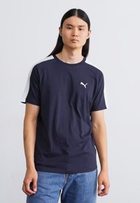 Marineblå T-shirt med korte ærmer og hvide detaljer på skuldrene. Har et lille hvidt logo på brystet. Lavet af blødt, letvægtsstof.