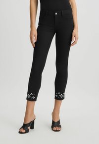 Jeans capri negre din denim, cu un design ajustat, împodobite cu detalii de mărgele florale la tiv. Purtați cu sandale negre cu toc.