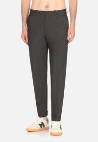 Pantaloni grigi scuri, slim-fit, con chiusura a bottone, texture liscia e tasche laterali, abbinati a sneakers bianche con dettagli neri.